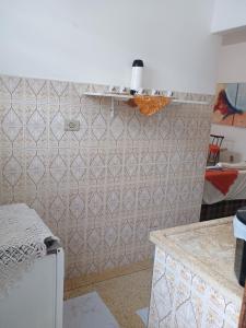 a kitchen with a white tiled wall at Kitnet in Praia Grande