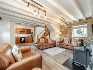 ein Wohnzimmer mit Ledermöbeln und einem TV in der Unterkunft Old Stables Cottage in Blaenporth