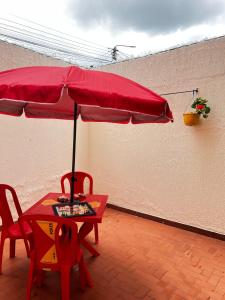 a red table with two chairs and a red umbrella at Casa Rincón in Curití