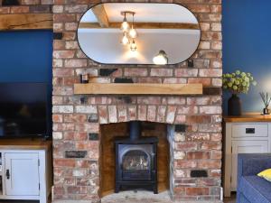 a brick fireplace in a living room with a mirror at Brookfields in Slingsby