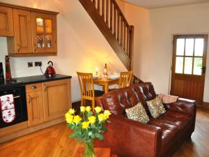 a living room with a couch and a table with yellow flowers at The Old Dairy - Cottage in Crosscanonby