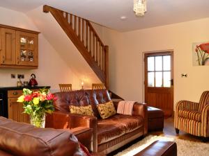 a living room with a leather couch and a staircase at The Old Dairy - Cottage in Crosscanonby +13 photos