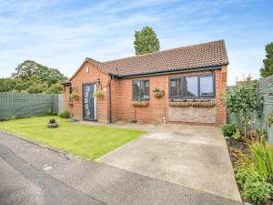a brick house with a garden and a driveway at The Hideaway in Chapel Saint Leonards
