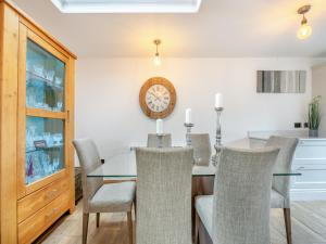 a dining room with a table and chairs and a clock at The Hideaway in Chapel Saint Leonards