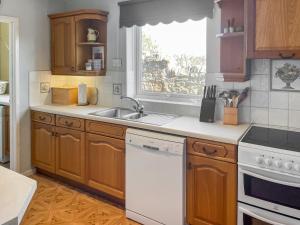 eine Küche mit Holzschränken und einem weißen Geschirrspüler in der Unterkunft Shepherd's Cottage - Uk48872 in Belford
