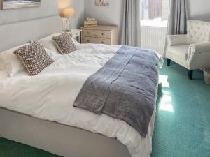 ein Schlafzimmer mit einem weißen Bett mit einer Decke darauf in der Unterkunft Shepherd's Cottage - Uk48872 in Belford