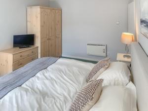 ein Schlafzimmer mit einem weißen Bett und einem Fernseher in der Unterkunft Shepherd's Cottage - Uk48872 in Belford + 14 Fotos