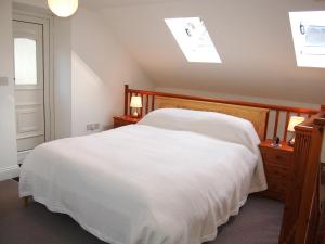 a bedroom with a large white bed and a window at Woodstore Cottage in Lazonby