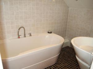 a bathroom with a white tub and a sink at Woodstore Cottage in Lazonby +6 photos