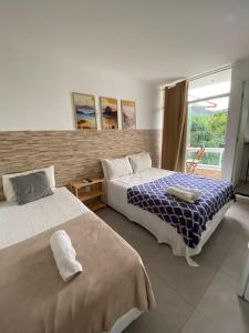 ein Schlafzimmer mit zwei Betten und einem Fenster in der Unterkunft Pousada MarÍsis Barra da Tijuca in Rio de Janeiro