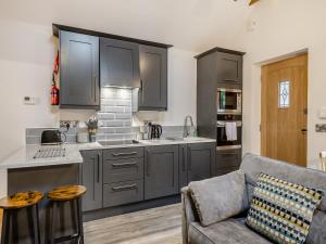 Wainfleet All SaintsにあるThe Mash Room- Uk34819のグレーのキャビネットとソファ付きのキッチンが備わります。