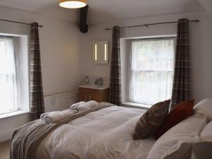 a bed in a bedroom with two windows at Acorn Lodge Cottage in Keswick +14 photos