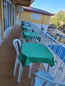 a row of green tables and chairs on a balcony at Pousada Essenza lindoía in Águas de Lindóia +19 photos