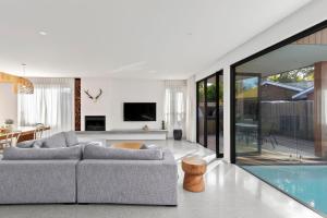 a living room with a couch and a swimming pool at Riverhaus Luxe Barwon Heads Retreat with Pool in Barwon Heads