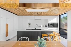 a kitchen with white walls and a wooden ceiling at Riverhaus Luxe Barwon Heads Retreat with Pool in Barwon Heads
