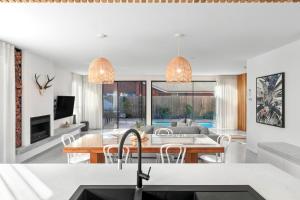 a kitchen and living room with a table and chairs at Riverhaus Luxe Barwon Heads Retreat with Pool in Barwon Heads +22 photos