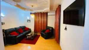 a living room with a black leather couch and red pillows at Flat Hôtel Alpha in Kinshasa