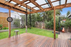 un patio con una terrazza in legno con un orologio sopra di Jan Juc Coastal Retreat 500m to Beach Pet Friendly a Torquay