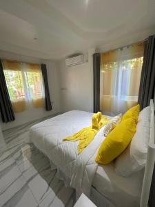 a bedroom with a white bed with yellow pillows at Agape Suites-Room 1- Ground Floor in Soufrière