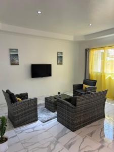 a living room with couches and a flat screen tv at Agape Suites-Room 1- Ground Floor in Soufrière