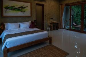 a bedroom with a bed and a large window at Elforest 3 in Payangan
