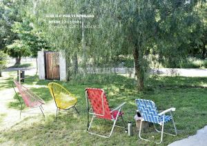 three chairs sitting in the grass under a tree at Casa Amplia a 10 cuadras del mar in Necochea