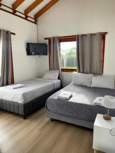 a room with two beds and a tv and a window at Villa Ancestral in Villa de Leyva