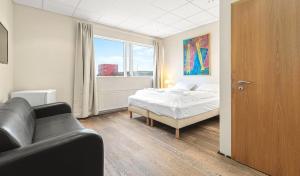 a bedroom with a bed and a couch and a window at T10 Self check-in Hotel in Hafnarfjördur