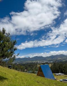 a barn with a blue roof on top of a hill at La Alejandría de Guasca in Guasca