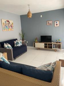 ein Wohnzimmer mit Sofa und Fernseher in der Unterkunft Casa aconchegante em condomínio arborizado in Pipa