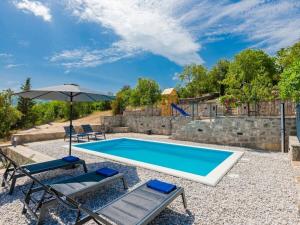 a swimming pool with two chairs and an umbrella at Green Paradise with pool in Dropuljići