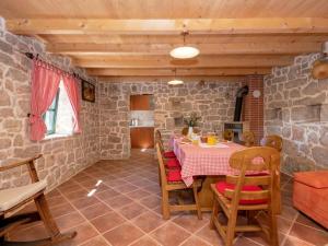 a dining room with a table and chairs and a stone wall at Green Paradise with pool in Dropuljići