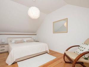 a white bedroom with a bed and a chair at Green Paradise with pool in Dropuljići +20 photos