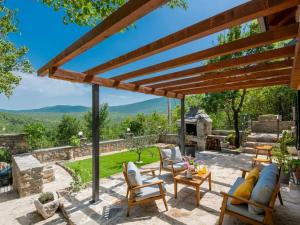 a patio with a wooden pergola and chairs at Green Paradise with pool in Dropuljići
