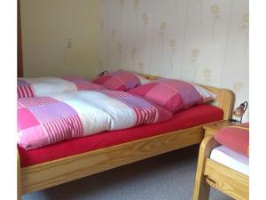 ein Bett mit rosa und weißen Decken und Kissen darauf in der Unterkunft 2 in the holiday home Am Waldweg in Arnoldshammer