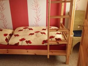 a bunk bed with a white bedspread with red flowers at To the horse paddock in Zislow
