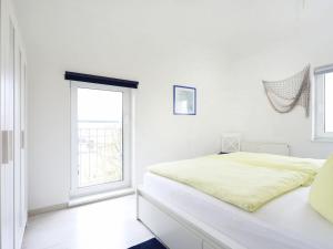a white bedroom with a bed and a window at Residence at the Spa Park 1 in Warnemünde