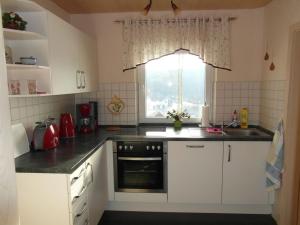 une cuisine avec des armoires blanches, un évier et une fenêtre dans l'établissement 1 in the holiday home Am Waldweg, à Arnoldshammer