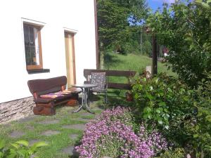 un jardin avec un banc, une table et des fleurs dans l'établissement 1 in the holiday home Am Waldweg, à Arnoldshammer
