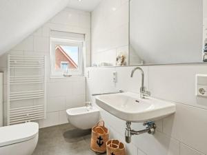 a white bathroom with a sink and a toilet at Holiday home in Timmel with swimming pool in Timmel +17 photos