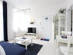 a white living room with a couch and a tv at Residence at the Spa Park 2 in Warnemünde +10 photos