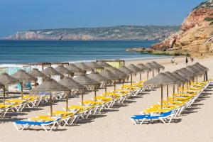 a bunch of chairs and umbrellas on a beach at NAU Salema Beach Village in Salema