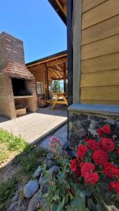 un montón de flores rojas delante de un edificio en Cabaña Ty Bryn, en Trevelín