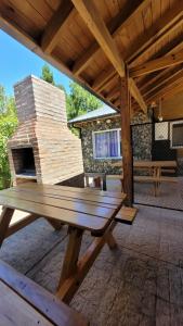 a wooden picnic table on a patio with a stone fireplace at Cabaña Ty Bryn in Trevelín +5 photos