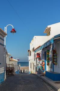 a street with buildings and the ocean in the background at NAU Salema Beach Village in Salema