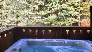 ein Whirlpool auf einer Terrasse mit einem Holzzaun in der Unterkunft Crystal Forest #11 By Bear Country in Sun Peaks + 25 Fotos