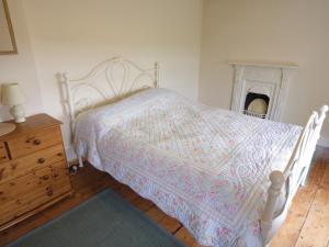 a bedroom with a bed and a dresser and a fireplace at Riffli - Hw7700 in Abersoch