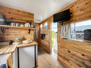 een keuken met houten wanden en een tv in een klein huis bij The Box - Oasis Farm in Fareham