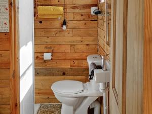 a bathroom with a toilet and wooden walls at The Box - Oasis Farm in Fareham