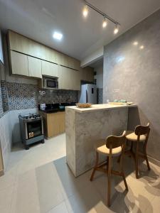 a kitchen with a counter and two chairs and a stove at Quarto em Belém - Próximo ao Mercado de São Brás in Belém